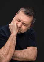 dolor de cabeza. hombre con la cara cerrada a mano foto