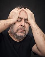 Headache. Man with face closed by hand photo