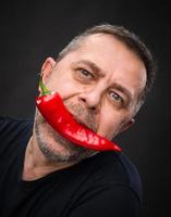 elderly man with red pepper in his mouth photo