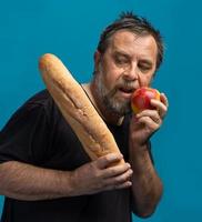 el hombre sostiene la manzana en una mano y el pan en la otra foto
