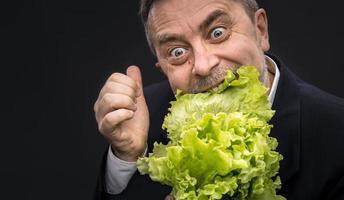 hombre sosteniendo y comiendo lechuga foto