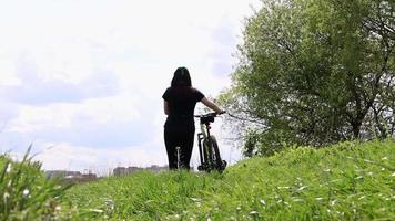 Young woman travels by bike. adventure and travel concept. A healthy tourist is walking with a bicycle, enjoying the nature and the sun. The girl rolls the bike. sport women lifestyle. video