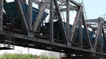 um trem de carga passa por uma velha ponte de aço sobre o rio. ponte ferroviária sobre a qual o trem passa. conceito de transporte. video