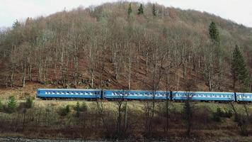 Ein alter Zug fährt im Herbst an einem nebligen Tag Rauch auf Schienen in die Berge. Personenzug fährt durch den Wald. video