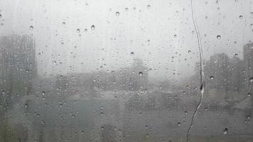 Nahaufnahme von Wassertropfen auf Glas. Während des Herbstregens fallen große Tropfen auf die Fensterscheibe und fließen tagsüber gegen den Himmel. Herbst- und Regenzeitkonzept. schlechtes Wetter. video