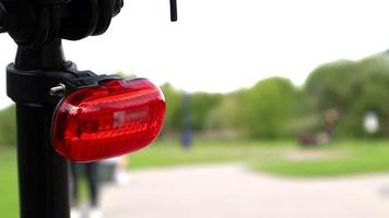 Flashing LED red taillight mounted on a bicycle close-up in the daytime. The back of the bike with a red frame warning light. video