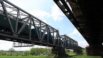 un tren de carga pasa sobre un viejo puente de acero que cruza el río. puente ferroviario sobre el que pasa el tren. concepto de transporte video