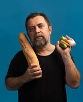 Man holds vegetables in one hand and bread in other photo