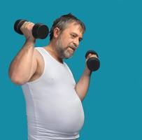 Fat middle-aged man exercising with dumbbells photo