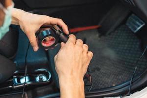 Hand of mechanic using duct tape wrapping wire of car to install device photo