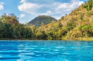 Swimming pool by the tropical rainforest on sunny day at the tropical resort photo