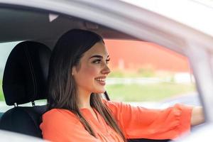 Linda señorita feliz conduciendo coche. imagen de una hermosa joven conduciendo un auto y sonriendo. retrato de una feliz conductora conduciendo un coche con cinturón de seguridad foto