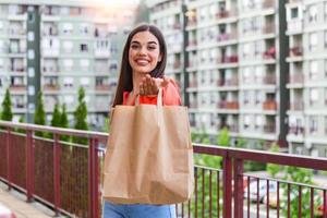 Woman delivering food in paper bag.Female volunteer holding groceries in the house porch. Delivery food service at home. Courier delivered the order no name bag with food. photo