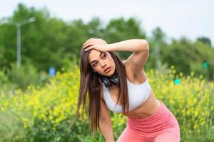 mujer joven cansada descansando después de trotar al aire libre. chica determinada sudando y descansando después de correr duro. mujer con curvas agotada relajándose después de correr en el parque con ejercicio de respiración. foto