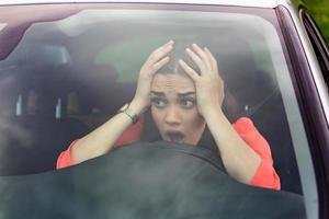Stressed woman driver sitting inside her car. Angry female driver driving a car. Angry young woman stuck in a traffic jam. Woman annoyed in car. Girl stuck in traffic. photo