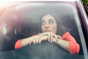 Stressed woman driver sitting inside her car. Sad female driver driving a car. young woman stuck in a traffic jam. Woman annoyed in car. Girl stuck in traffic. photo