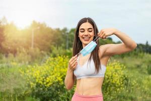 Coronavirus is over we won concept. Woman holding mask. We won sign outdoor in the sunshine freedom. We are safe. Coronavirus ended. We won. No more quarantine. Breathe deep. Take off the mask. Cure. photo