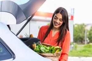 Close up portrait of a happy pretty girl holding bag with groceries and looking at camera with copy space. Close up of a woman holding heavy bag with groceries. Carrying a healthy bag