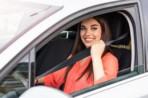 Safety first. Beautiful Caucasian lady fastening car seat belt. Pretty young woman driving her new car. Pretty young woman driving her new car. Female fastening safety belt in car photo