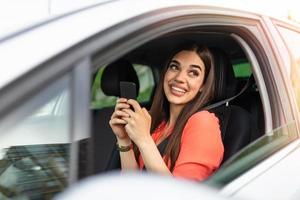 Nice beautiful young woman smile and use mobile phone touching the screen inside the car while travel. modern concept of search hings and contact friends when you are away. daily use of smartphone photo