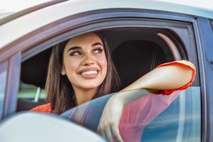 mujer joven sentada en un coche. mujer feliz conduciendo un coche y sonriendo. retrato de una feliz conductora conduciendo un coche con cinturón de seguridad. Linda señorita feliz conduciendo coche. foto