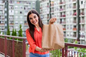 mujer haciendo compras para vecinos mayores. mujer hermosa joven sosteniendo una bolsa de papel para llevar de la entrega foto
