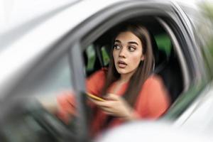 Texting and driving, behind the wheel. Breaking the law. Woman driving car distracted by her mobile phone causing an accident photo