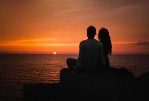 Young couple in love against sunset at sea photo