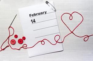 Calendario del 14 de febrero con corazón de hilo textil y botones. foto