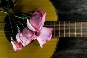 un ramo de rosas rosas en las cuerdas de la guitarra foto