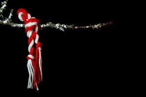 un martisor atado en una rama sobre un fondo negro foto