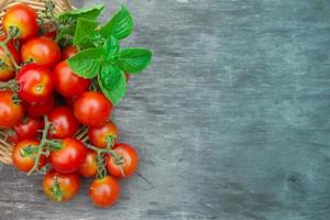 tomates cherry frescos, albahaca y orégano sobre fondo rústico de madera envejecida foto