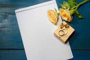 box of rings on the table with roses and a note photo