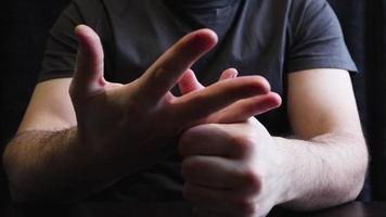 Ein Mann bricht sich die Knöchel und Finger. Knöchel knacken auf dem Tisch. Nahaufnahme der Hand des Mannes mit grauem Hintergrund. video
