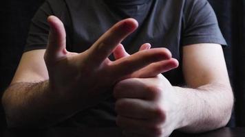 un homme se casse les jointures et les doigts. claquer des jointures sur la table. gros plan de la main de l'homme avec un fond gris. video