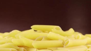 Slowly spinning raw Penne Rigate is a short pasta with oblique cuts and a ribbed surface. Traditional Italian pasta. Doesn't get stuck. Close-up side view. video