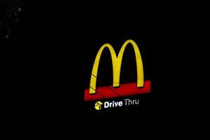 Glowing McDonalds restaurant sign against night sky. Logo of Mcd Drive Thru. photo