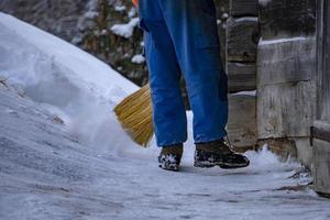 man cleaning snow with a broom photo