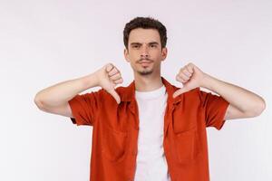 Portrait of young man shows sign of dislike, looks with negative expression and disapproval on isolated background photo