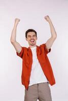 Portrait of happy joyful young man standing doing winner gesture clenching fists keeping isolated on white color wall background studio photo