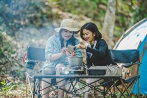 Asian pretty woman and friend use smartphone selfie on camping photo