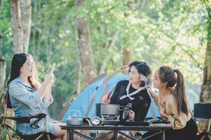 Young women cooking and use smartphone take photo on camping