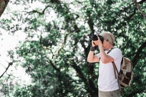 Asian traveler man with backpack taking a photo in the park