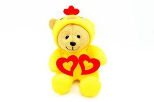 Valentine's day, love or lovely concept. Teddy bear doll in yellow chicken dress style holding two red hearts isolated on white background. Cute object or toy and gift for special day. photo
