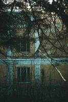 Close up abandoned multi storey building with overgrown fir branches concept photo