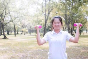 Strong healthy concept, women exercise in park with dumbbell photo