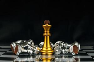 Winner. gold king surrounded with silver chess pieces on chess board game competition with copy space on dark background, chess battle, success, team leader, teamwork and business strategy concept