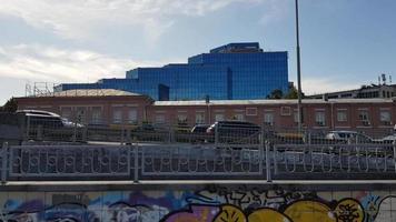 Side view of a city traffic jam. City landscape with cars. Cars in motion on a bridge against the background of a large glass building and old architecture in the city at daytime. video