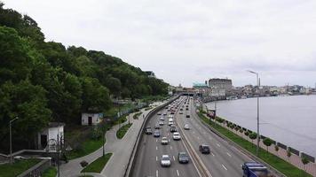 los coches circulan por el terraplén de la carretera en kiev, ucrania. tráfico en ambas direcciones en una carretera muy transitada. vista aérea del paisaje urbano. ucrania, kiev - 1 de junio de 2020. video