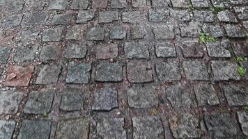 uma calçada molhada cria um cenário brilhante. estrada de pedra, pedras de pavimentação na cidade velha durante a chuva durante o dia. praming vertical de uma pessoa andando em primeira pessoa. video